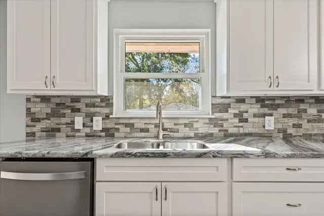 a bathroom with a granite countertop sink a mirror and a shower