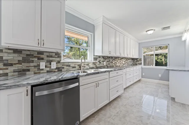 a kitchen with granite countertop a sink window and cabinets