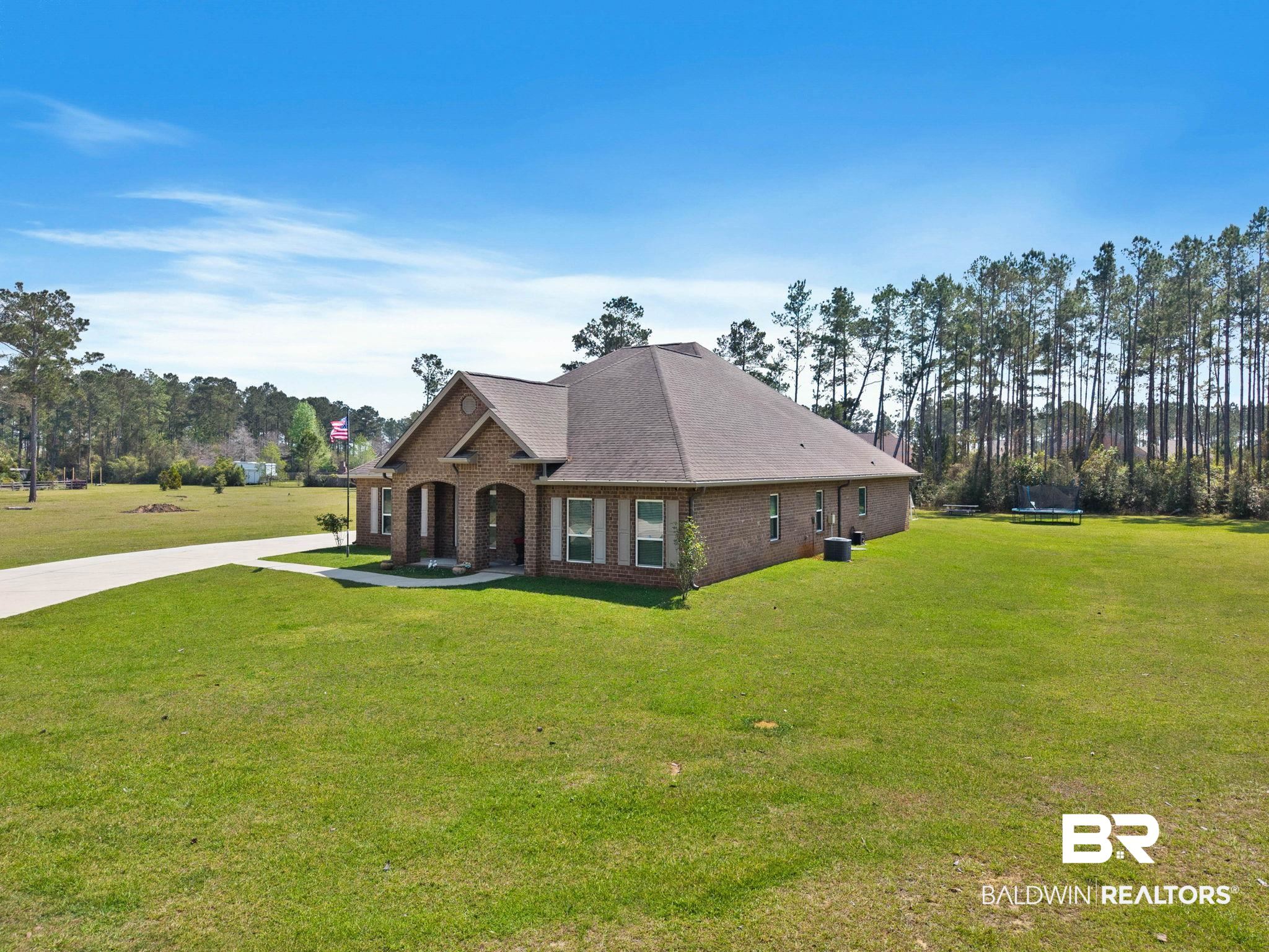 12750 B Jenkins Pit Road Daphne, AL 36527 - Photo 77 of 89 View of front facade featuring a front lawn, brick siding, view of scattered trees, and roof with shingles