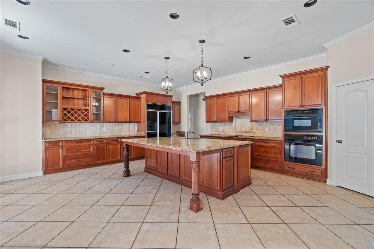 170 Jamerson Farm Road Collierville, TN 38017 - Photo 12 of 40 Kitchen featuring a kitchen bar, crown molding, black appliances, light tile patterned floors, and a center island with sink