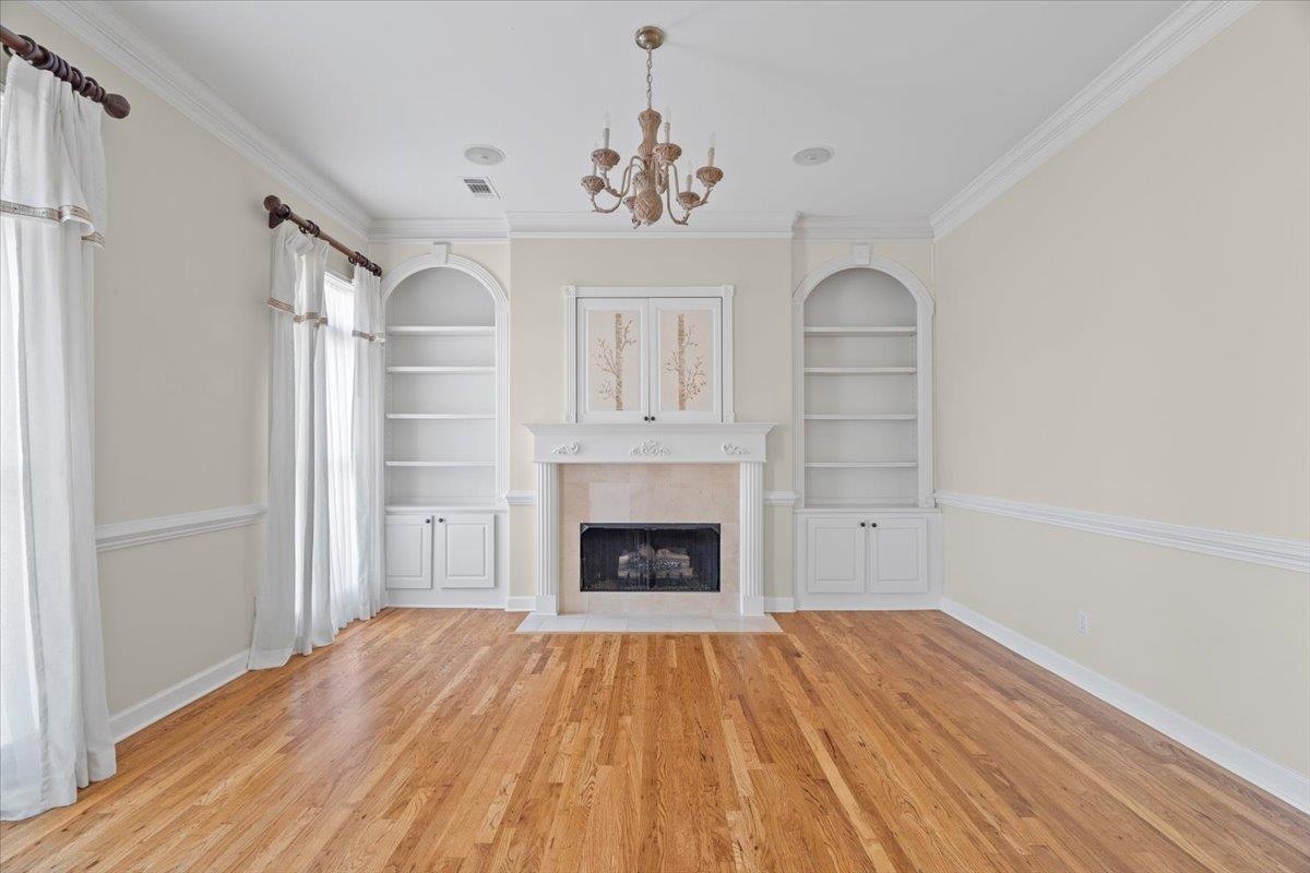 170 Jamerson Farm Road Collierville, TN 38017 - Photo 7 of 40 Unfurnished living room with light hardwood / wood-style flooring, an inviting chandelier, built in features, and ornamental molding