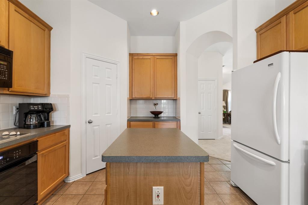 10903 Robincreek Lane Frisco, TX 75035 - Photo 8 of 17 a kitchen with a refrigerator a stove top oven a sink and cabinets
