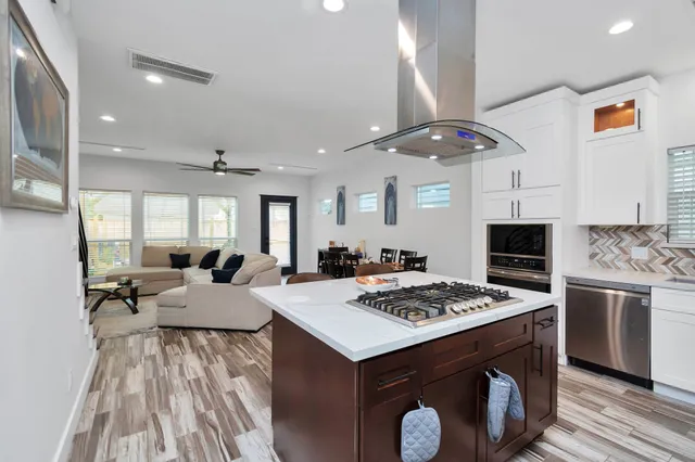 a kitchen with a stove a sink dishwasher and a refrigerator with wooden floor
