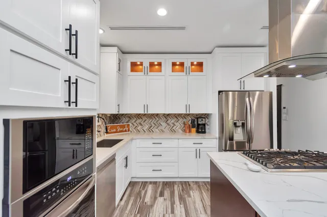 a kitchen that has a lot of cabinets a sink and appliances