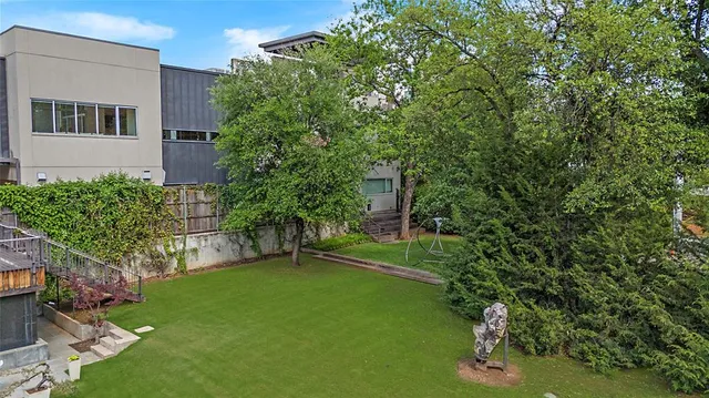 a view of a backyard with plants and a large tree