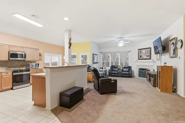 a living room with furniture a flat screen tv and kitchen view