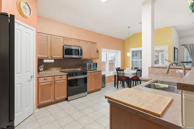 a kitchen with stainless steel appliances granite countertop a stove top oven a sink a dining table and chairs