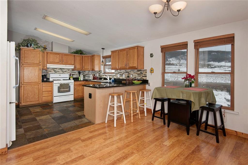 76 Lakeside Drive Dillon, CO 80435 - Photo 7 of 23 a kitchen with stainless steel appliances granite countertop a stove top oven a refrigerator a dining table and chairs with wooden floor