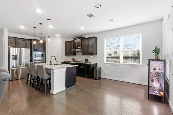 a large kitchen with kitchen island a counter top space a sink a refrigerator and cabinets