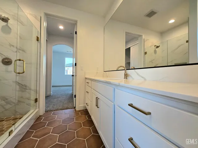 a bathroom with a double vanity sink a toilet and shower