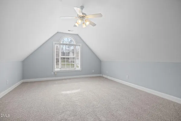 an empty room with a chandelier fan and windows