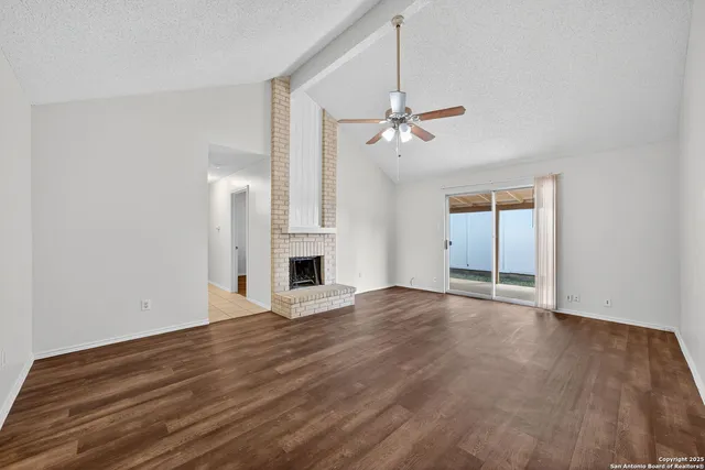 a view of empty room with wooden floor and ceiling fan