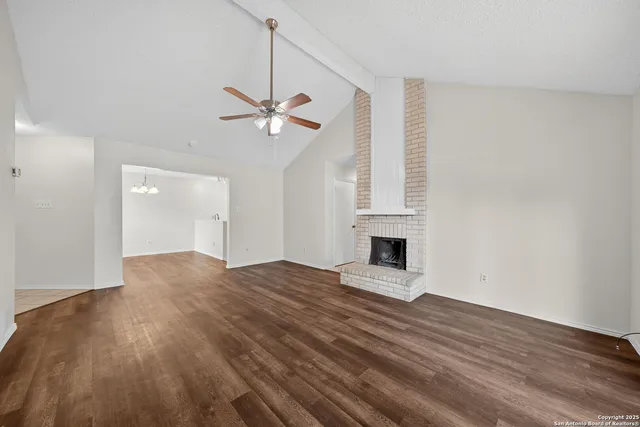 a view of empty room with wooden floor and fireplace