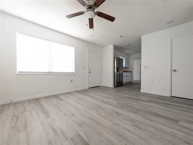 an empty room with wooden floor a ceiling fan and windows