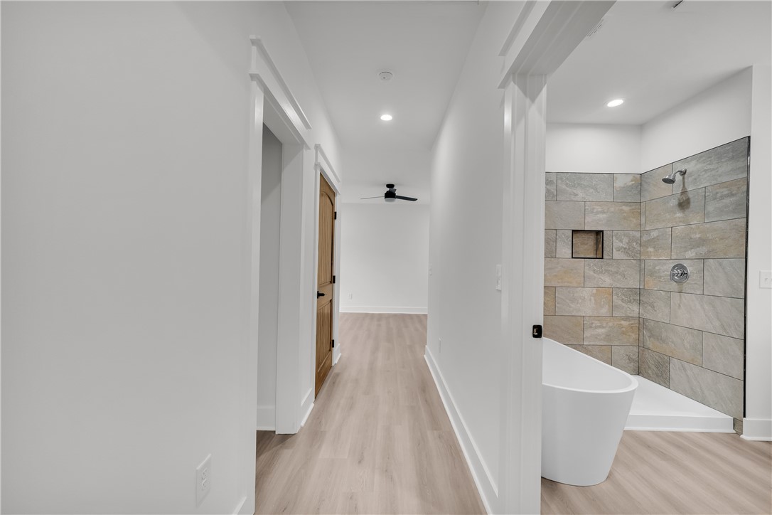 659 White Oak Farms Road Tamassee, SC 29686 - Photo 32 of 50 Clean lines and wood floors define this hallway leading past a modern bathroom setup.