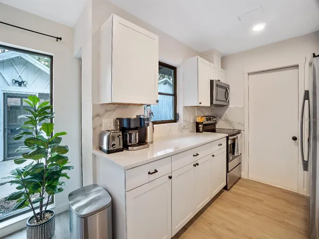 a kitchen with stainless steel appliances a white refrigerator a stove a microwave a sink and white cabinets