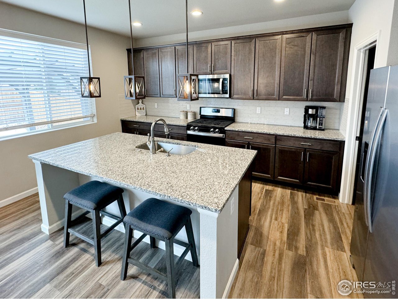 531 Ranchhand Drive Berthoud, CO 80513 - Photo 8 of 34 a kitchen with stainless steel appliances granite countertop a kitchen island a stove a sink dishwasher a dining table and chairs with wooden floor