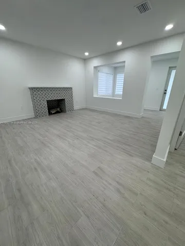 a view of empty room with wooden floor and fireplace