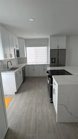 a kitchen with a sink a counter top space stainless steel appliances and a window
