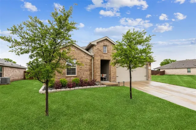 a front view of a house with a yard and tree