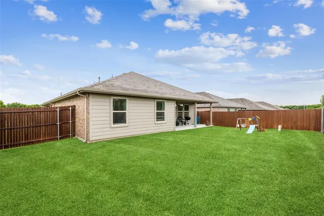 a view of a backyard with plants and large tree