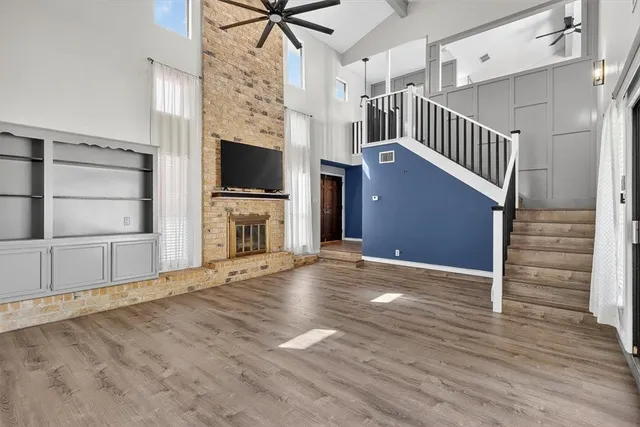 a view of an empty room with wooden floor fireplace and a window