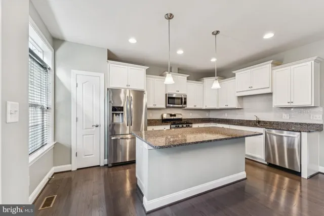 a open kitchen with white cabinets stainless steel appliances and wooden floor