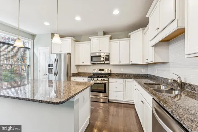 a large kitchen with stainless steel appliances granite countertop a refrigerator a sink and a stove