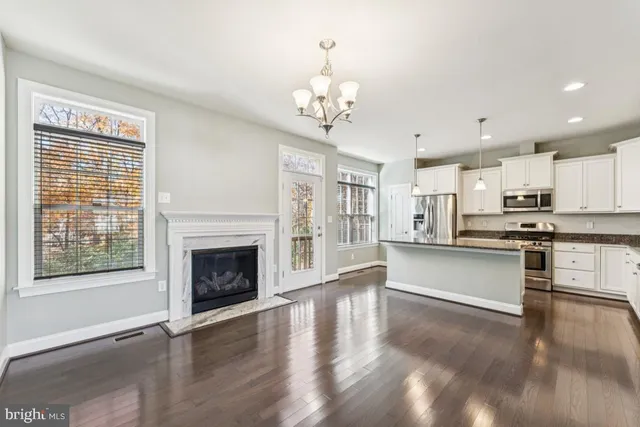 a large white kitchen with granite countertop a stove top oven a sink dishwasher and a fireplace with wooden floor