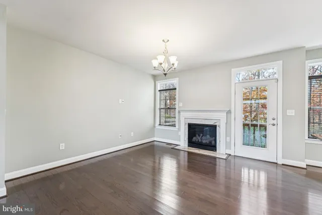 an empty room with wooden floor fireplace and windows