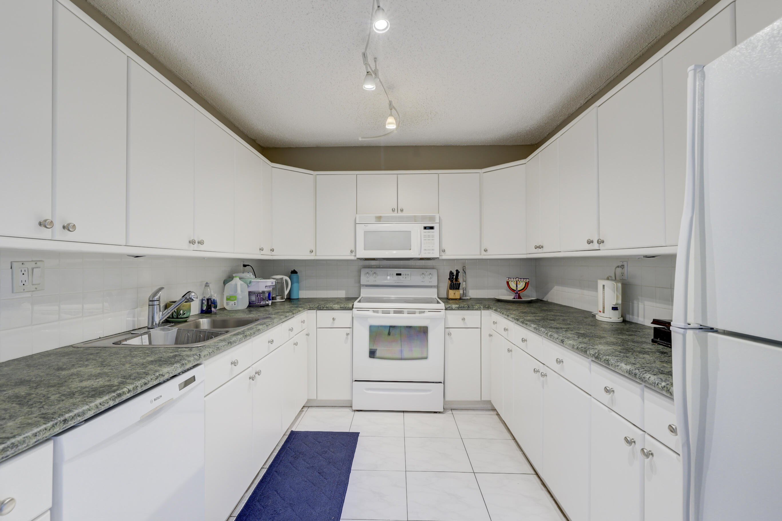 531 North Ocean Boulevard, Unit 710 Pompano Beach, FL 33062 - Photo 14 of 39 a kitchen with granite countertop white cabinets and white appliances