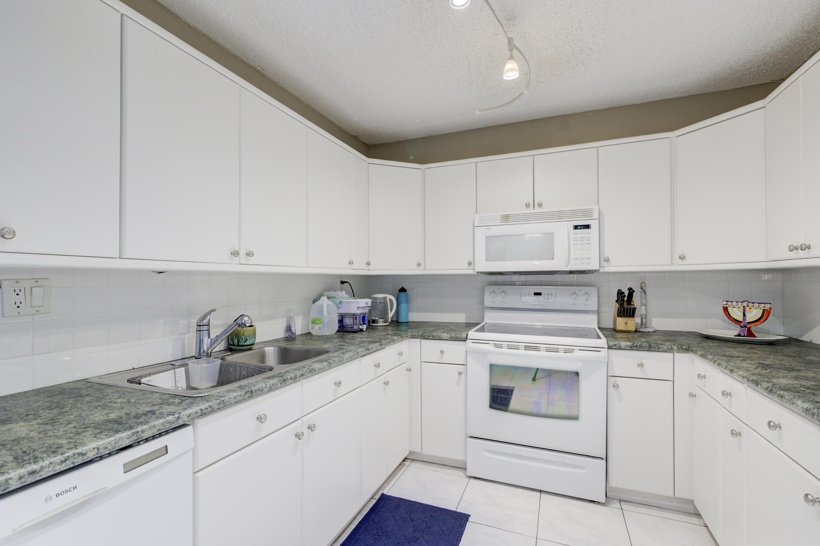 531 North Ocean Boulevard, Unit 710 Pompano Beach, FL 33062 - Photo 15 of 39 a kitchen with granite countertop white cabinets white appliances and sink