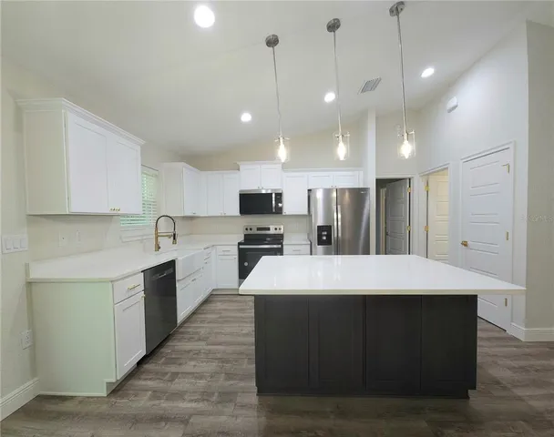 a large kitchen with kitchen island a stove a sink a center island and wooden floor