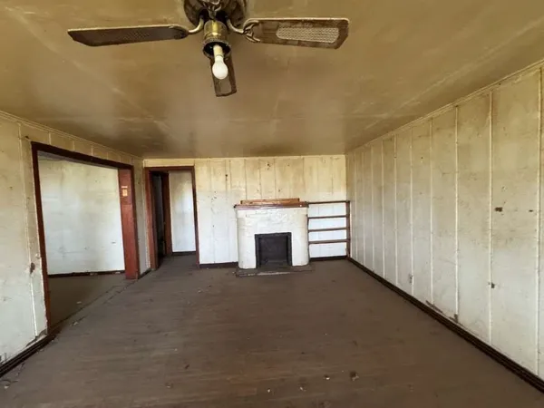 an empty room with windows and fireplace