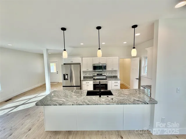 a kitchen with stainless steel appliances granite countertop a sink a stove and a refrigerator