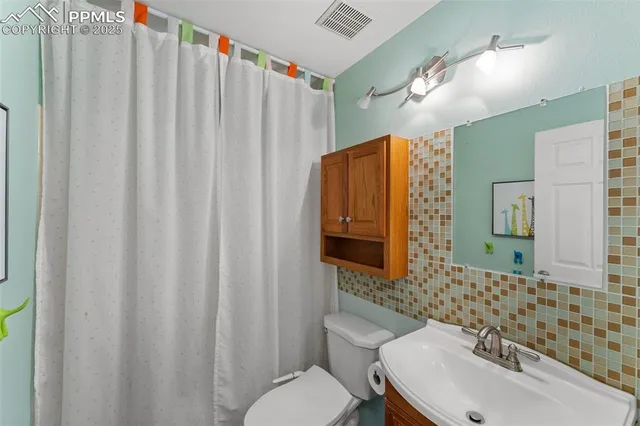 a bathroom with a sink a toilet and shower curtain