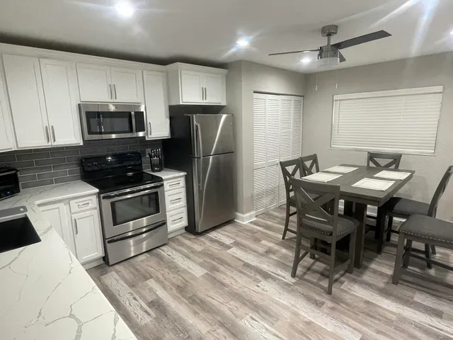 a kitchen with stainless steel appliances kitchen island granite countertop a table chairs microwave and refrigerator
