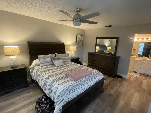 a bedroom with a bed a mirror on dresser and a flat screen tv