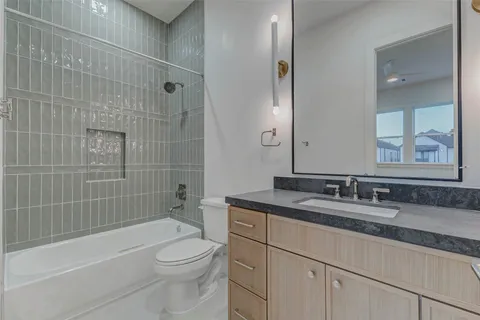 a bathroom with a granite countertop sink a toilet and shower
