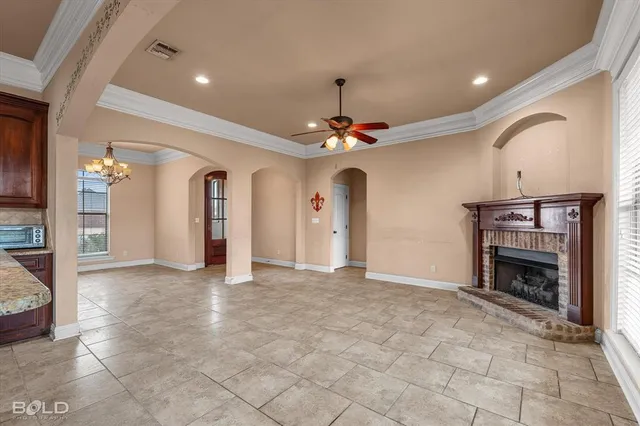 en empty room with a fireplace and chandelier