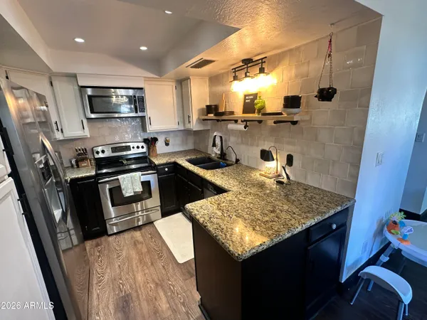 a kitchen with stainless steel appliances granite countertop a sink stove and refrigerator