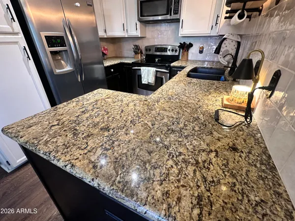 a kitchen with stainless steel appliances kitchen island granite countertop a sink stove and refrigerator