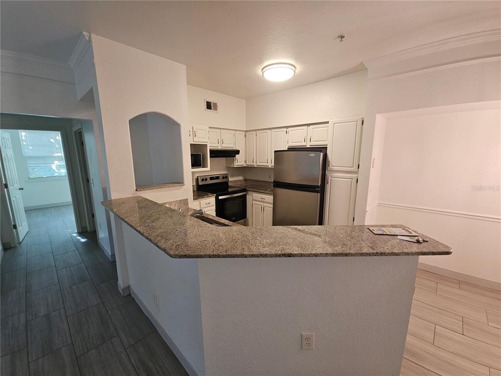 3446 Soho Street, Unit 108 Orlando, FL 32835 - Photo 8 of 39 a kitchen with kitchen island stainless steel appliances a sink and refrigerator