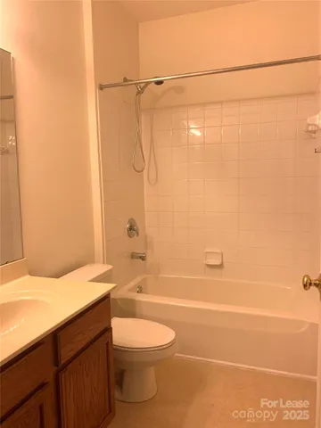 a bathroom with a granite countertop bathtub shower sink vanity and toilet