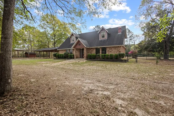 a sign that is sitting in front of a house with a tree