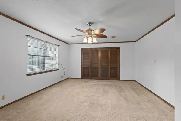 an empty room with chandelier fan and windows