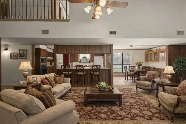 a living room with furniture couches and view of kitchen appliance