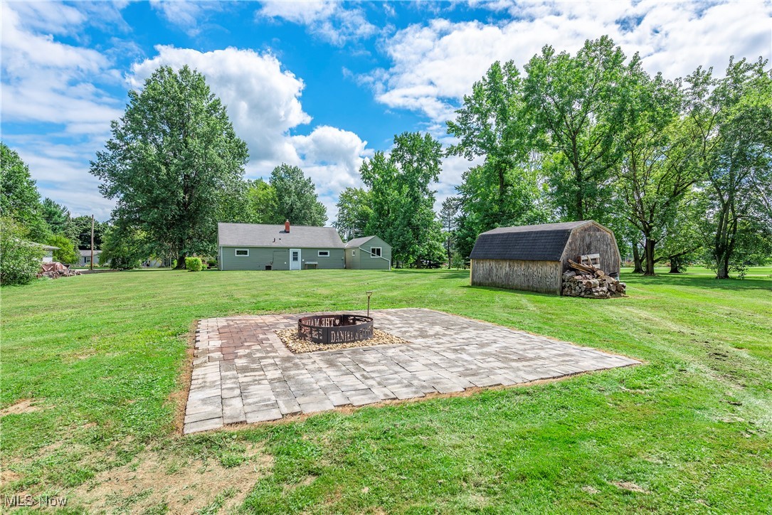 14808 Wheeler Road Lagrange, OH 44050 - Photo 40 of 50 View of grassy yard with a patio, an outdoor fire pit, an outdoor structure, view of wooded area, and a barn