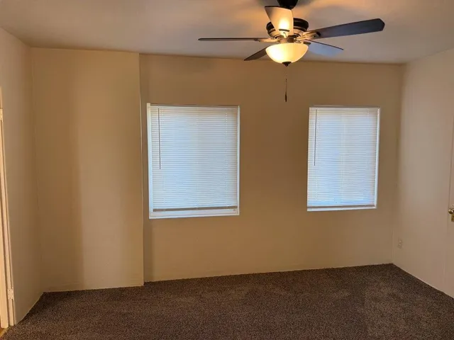 an empty room with windows and fan