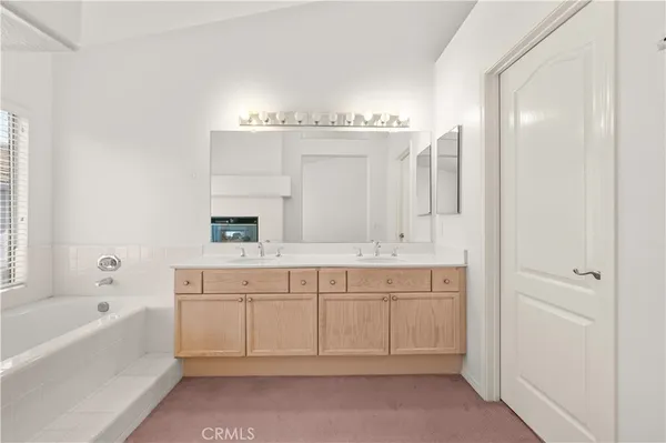 a spacious bathroom with a tub sink and mirror